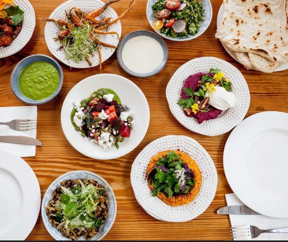 A private chef spread on a wooden table: colourful mezze plates, salads and warm flatbreads.